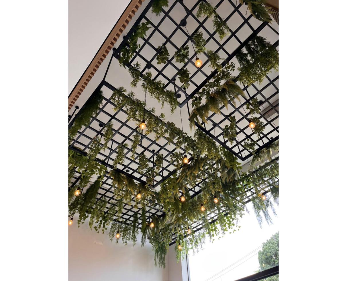 Estrutura de teto decorada com folhagens e iluminação