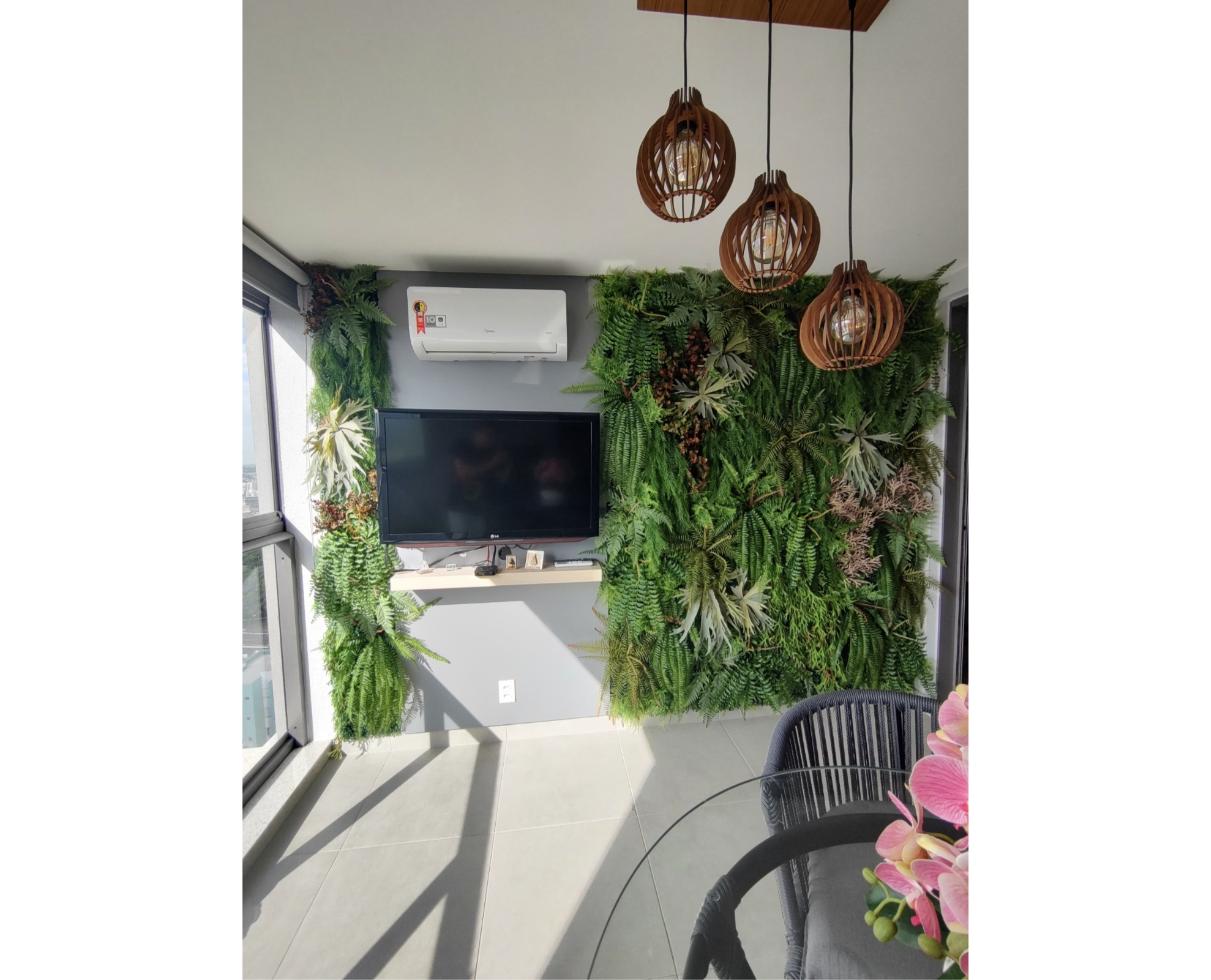 Jardim vertical ao redor da televisão em varanda residencial